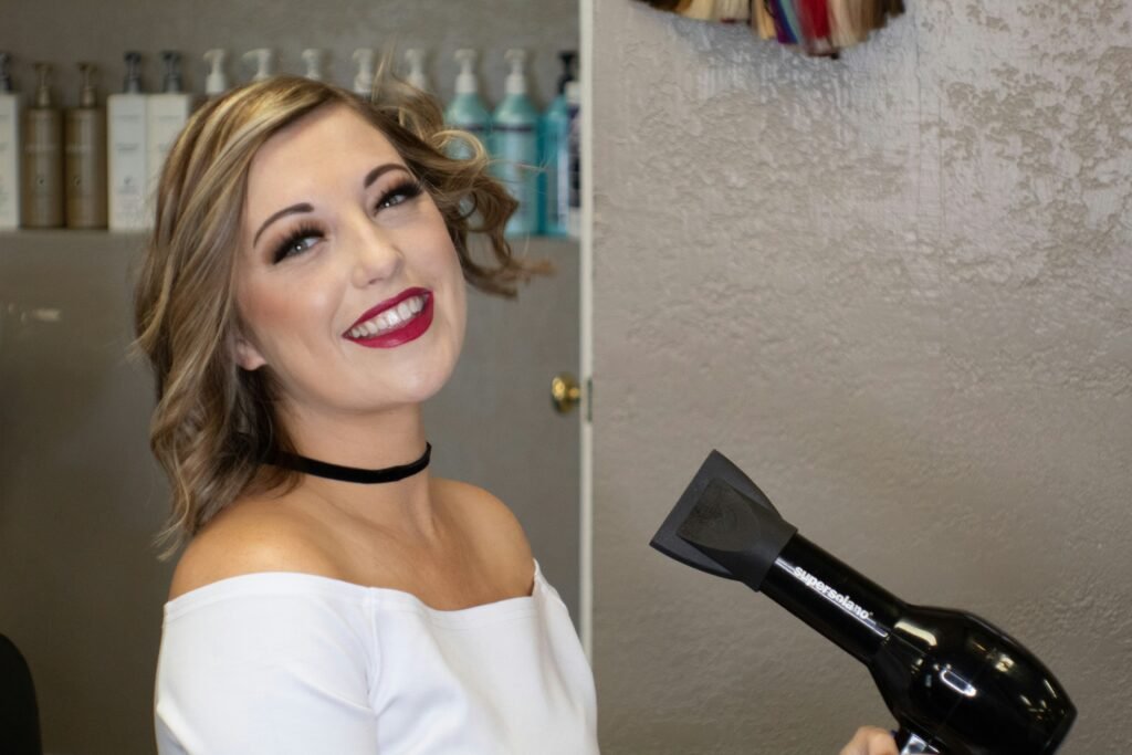 mulher sorrindo maquiada segurando secador de cabelos preto using a hair dryer correctly o guia definitivo de 2026 sobre como usar o secador de cabelo corretamente