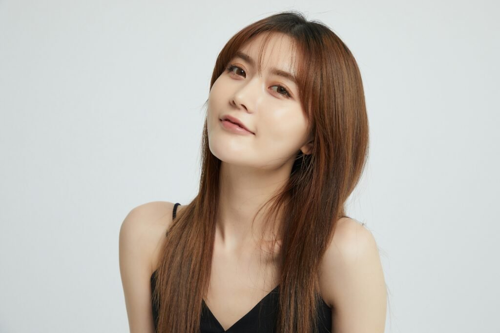 mulher sul coreana leve sorriso cabelos lisos longos soltos castanhos blusinha preta estilosa