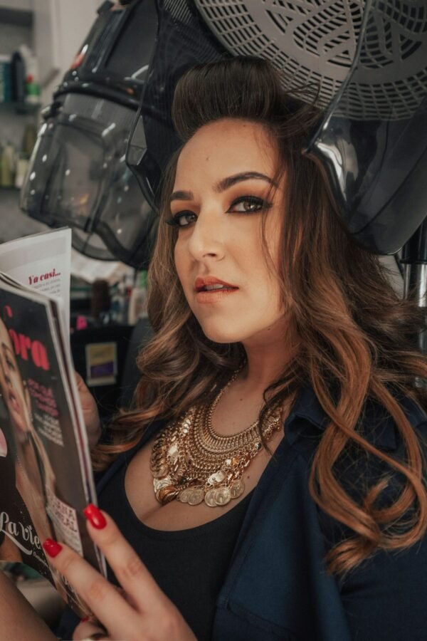 mulher maquiada cabelos longos lisos castanhos colar dourado grande estiloso lendo revista secando os cabelos foto de Eduardo Holguin unsplash.com