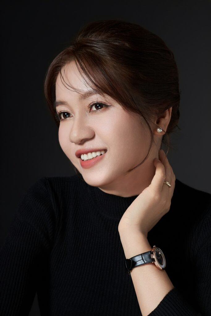 mulher sul coreana sorrindo cabelos lisos castanhos presos brinco pequeno perola blusinha preta