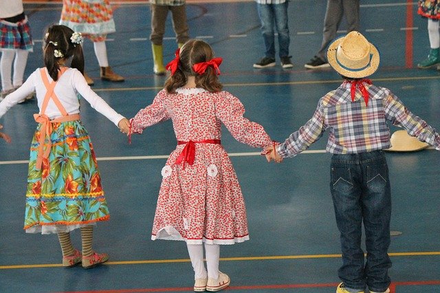 foto de três crianças que estão de costas e de mãos dadas dançando quadrilha festa junina
