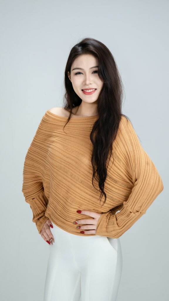 mulher sul coreana sorrindo cabelos lisos longos soltos blusinha estilosa marrom claro calca social branca unhas vermelhas