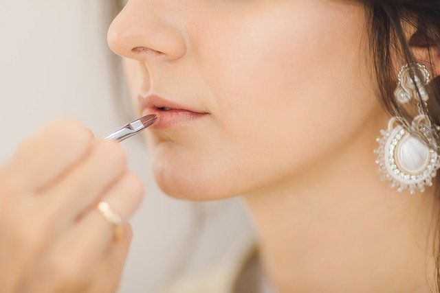 foto de metade do rosto de uma mulher pintando os labios