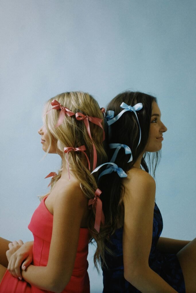 foto de duas mulheres uma loira e outra morena com cabelos longos e com varias fitas com lacinhos no cabelo