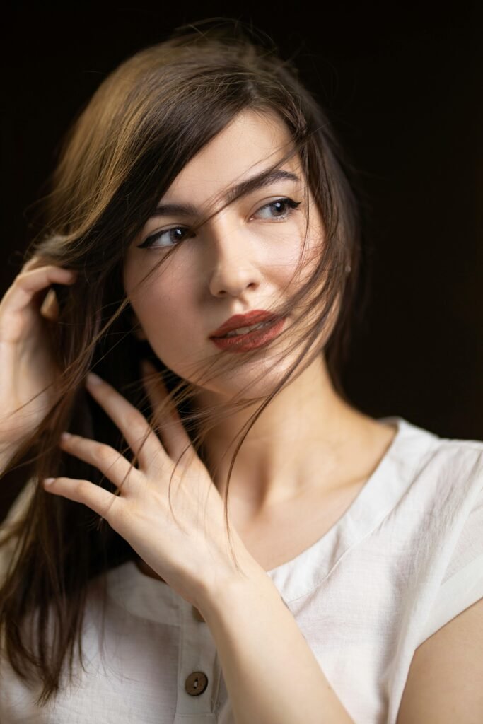 foto de perfil de mulher branca cabelos pretos longos leve maquiagem uma das mãos segurando os cabelos