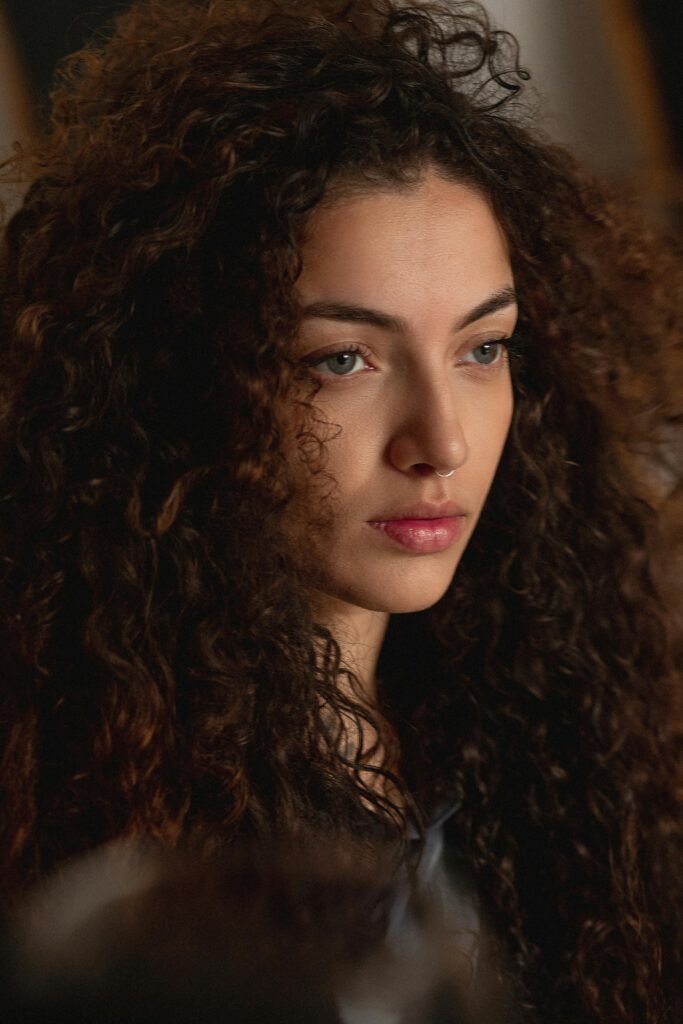 foto de perfil de uma mulher morena seria olhos verdes com percingi no nariz