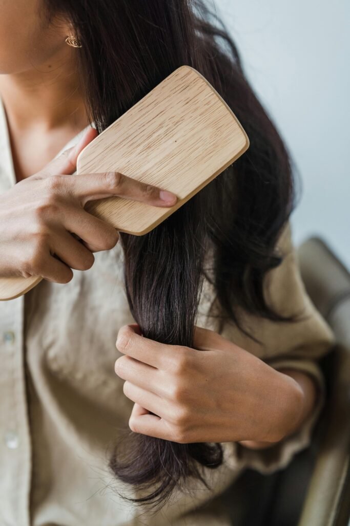 mulher com cabelos longos lisos pretos com uma escova desembaraçando os cabelos detangling hair brush escova de cabelo para desembaraçar