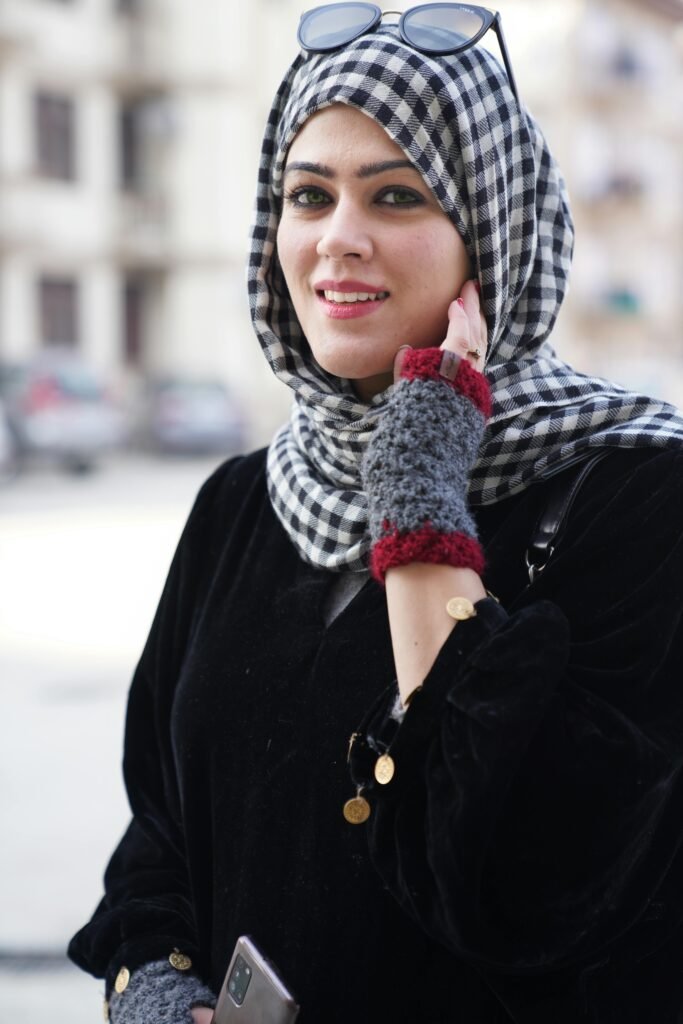 foto de mulher branca sorrindo com hijab xadrez branco e preto e óculos