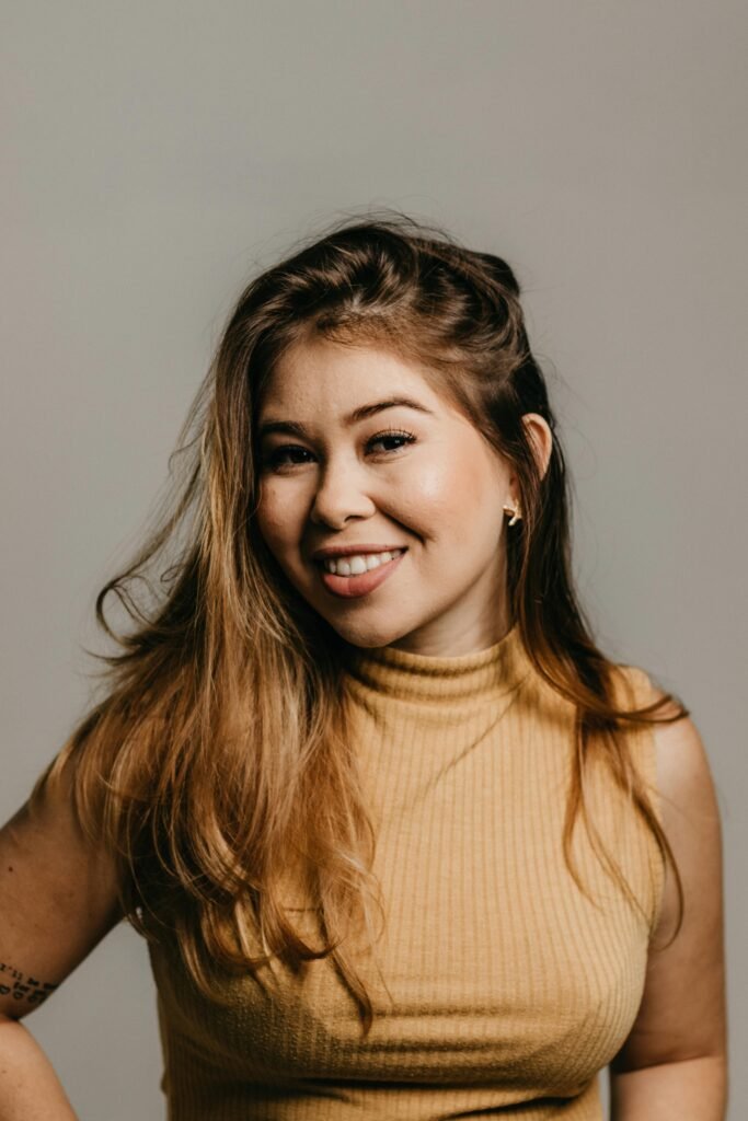 foto de perfil de mulher branca sorrindo cabelos loiros longos soltos leve maquiagem blusinha bege