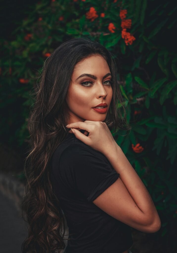 mulher maquiada cabelos longos lisos soltos olhos castanhos claros uma das mãos no queixo camiseta preta