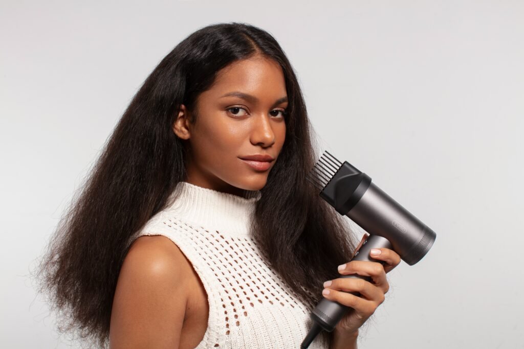 mulher segurando um secador de cabelos blusinha em croche branca estilosa cabelos longos lisos pretos