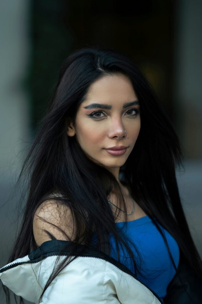 mulher maquiada leve sorriso batom nude cabelos longos lisos soltos pretos blusinha azul