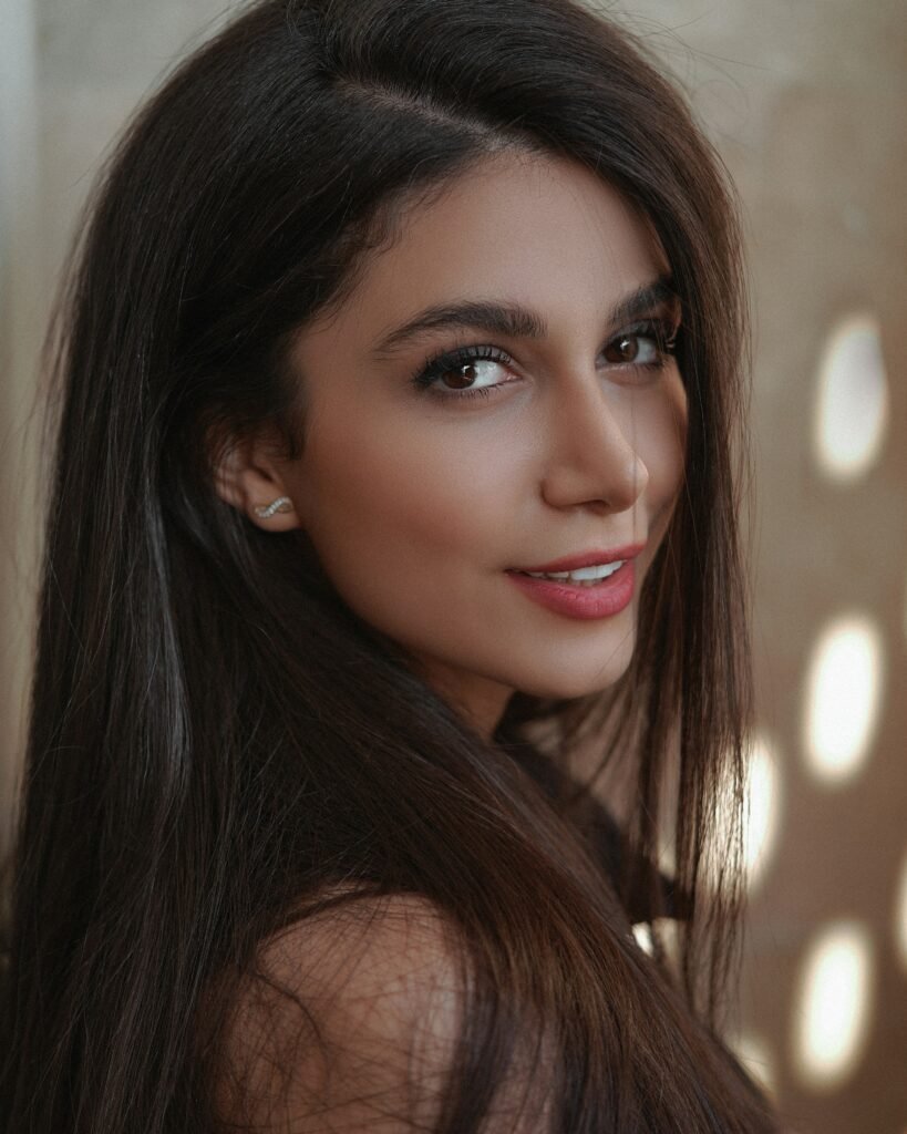 mulher sorrindo maquiada batom nude olhos castanhos brinco pequeno infinito cabelos lisos longos soltos castanhos