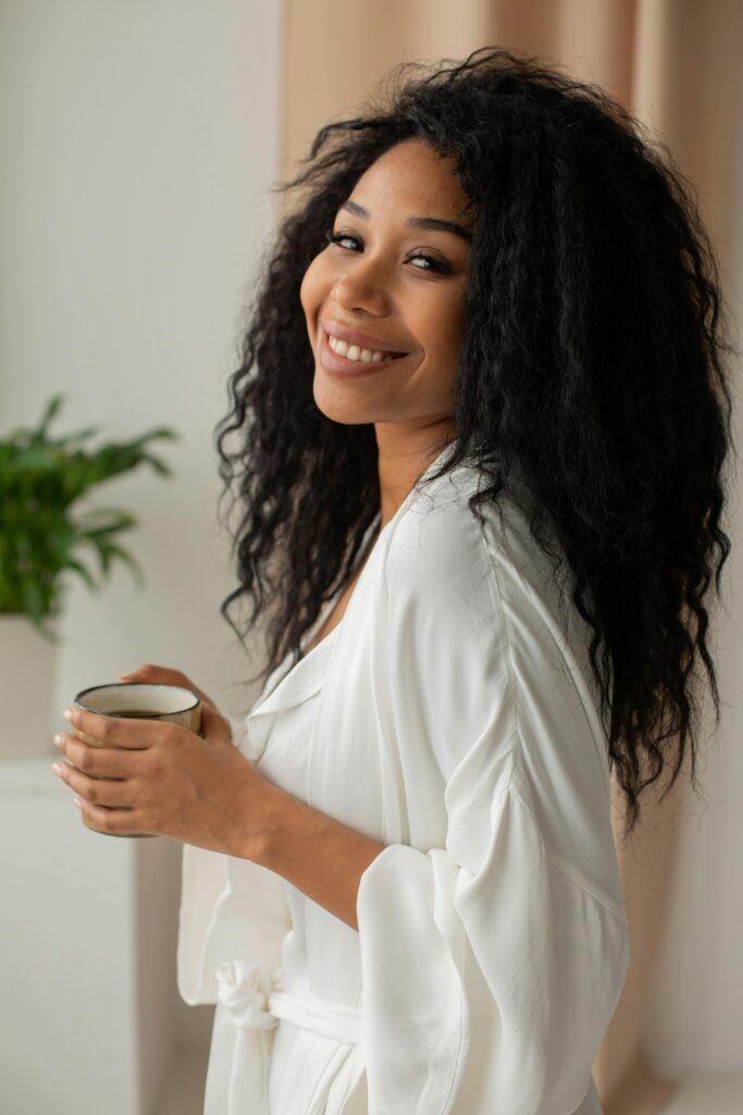 foto de mulher morena cabelos longos soltos pretos esta de roupão branco segurando uma xícara de cafe
