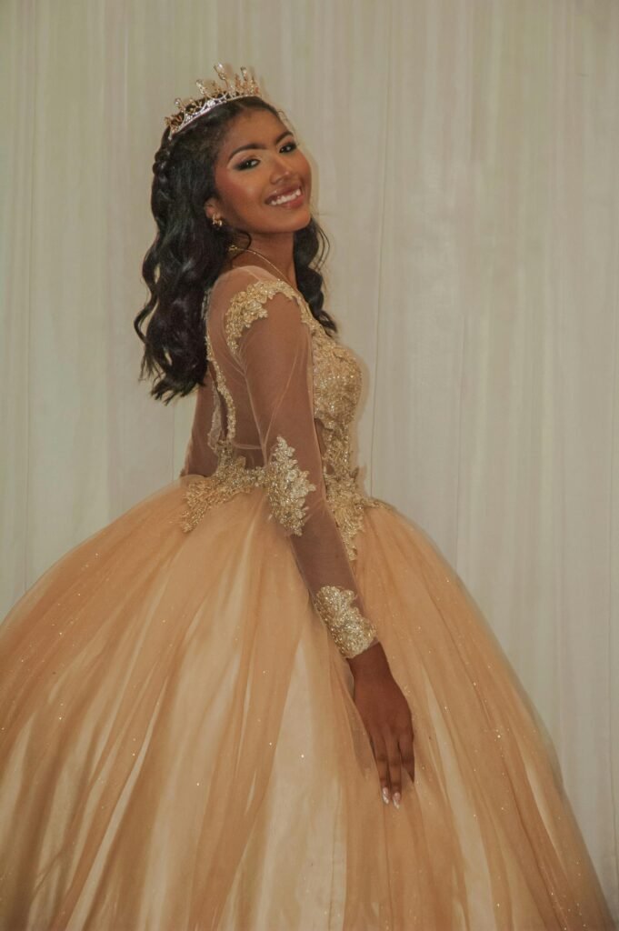 menina sorrindo comemorando seus 15 anos com vestido e coroa de princesa. vestido na cor bege longo e com rendas