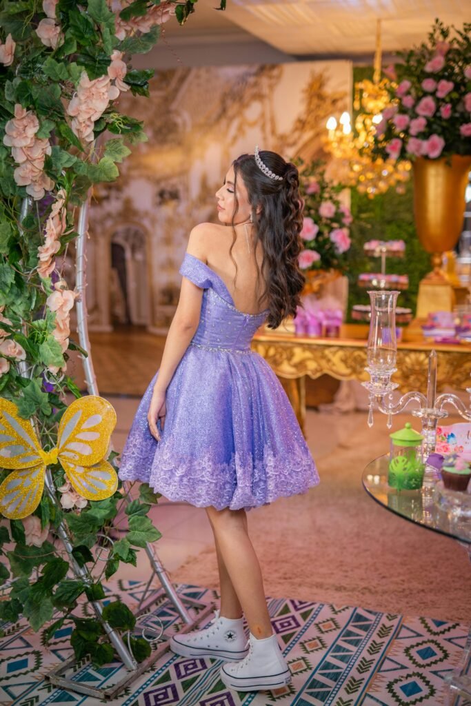 menina comemorando seus 15 anos esta de costas com vestido curto de princesa na cor lilas com rendinhas, tenis branco cano longo all star