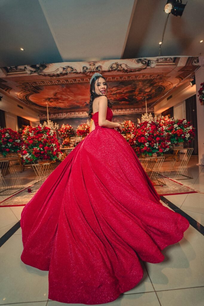 menina comemorando seus 15 anos com vestido longo de princesa na cor vermelha coroa de princesa