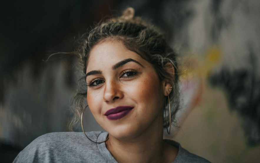 mulher morena cabelos lisos presos olhos castanhos brincos argolas grandes batom roxo purple lipstick, batom roxo 6 dicas de batom nada óbvias para você ousar