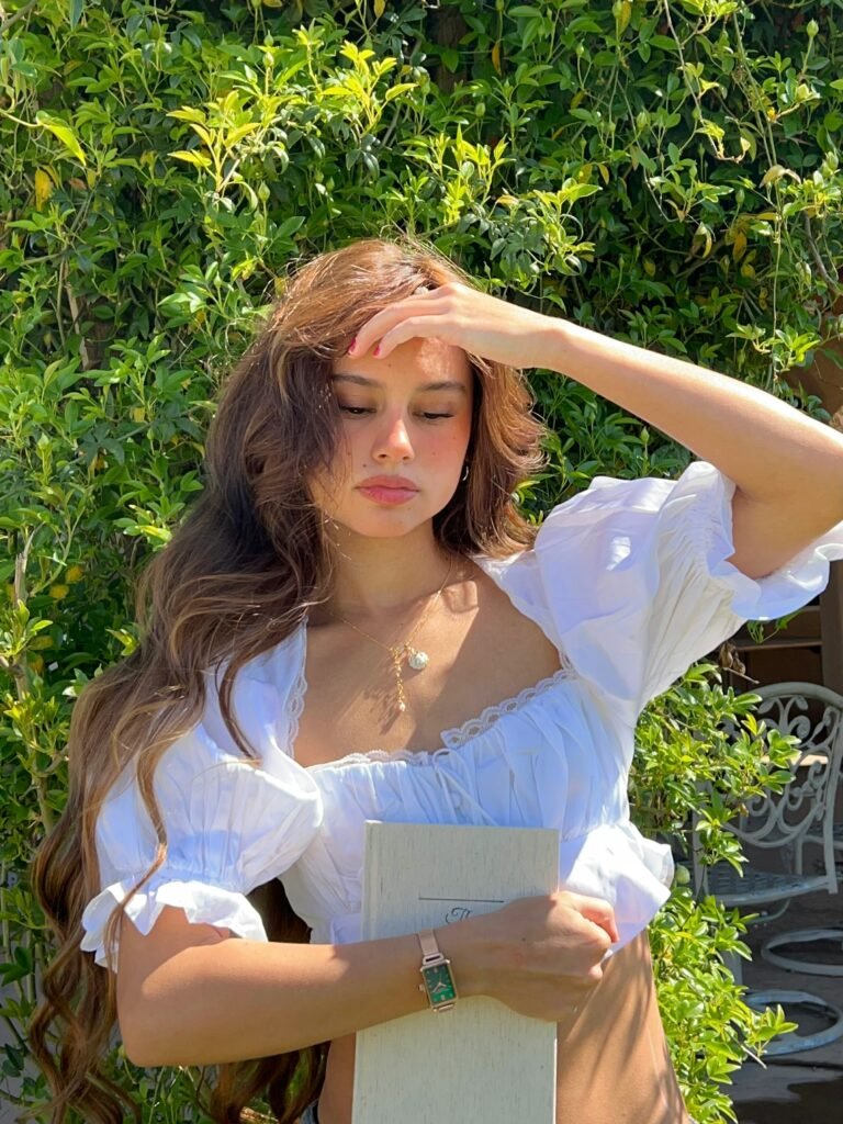 mulher cabelos compridos castanhos ondulados colar dourado com perola blusinha retro branca estilosa 