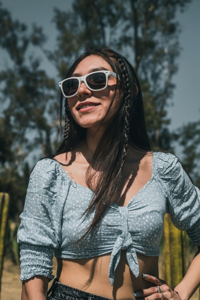 mulher sorrindo de óculos estiloso cabelos pretos lisos longos blusinha azul claro estilosa retro vintage