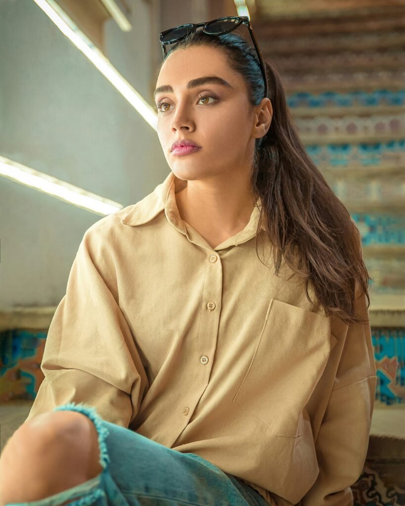 mulher maquiada batom roxo óculos na cabeça cabelos lisos longos castanhos camisa social bege calca jeans azul rasgada