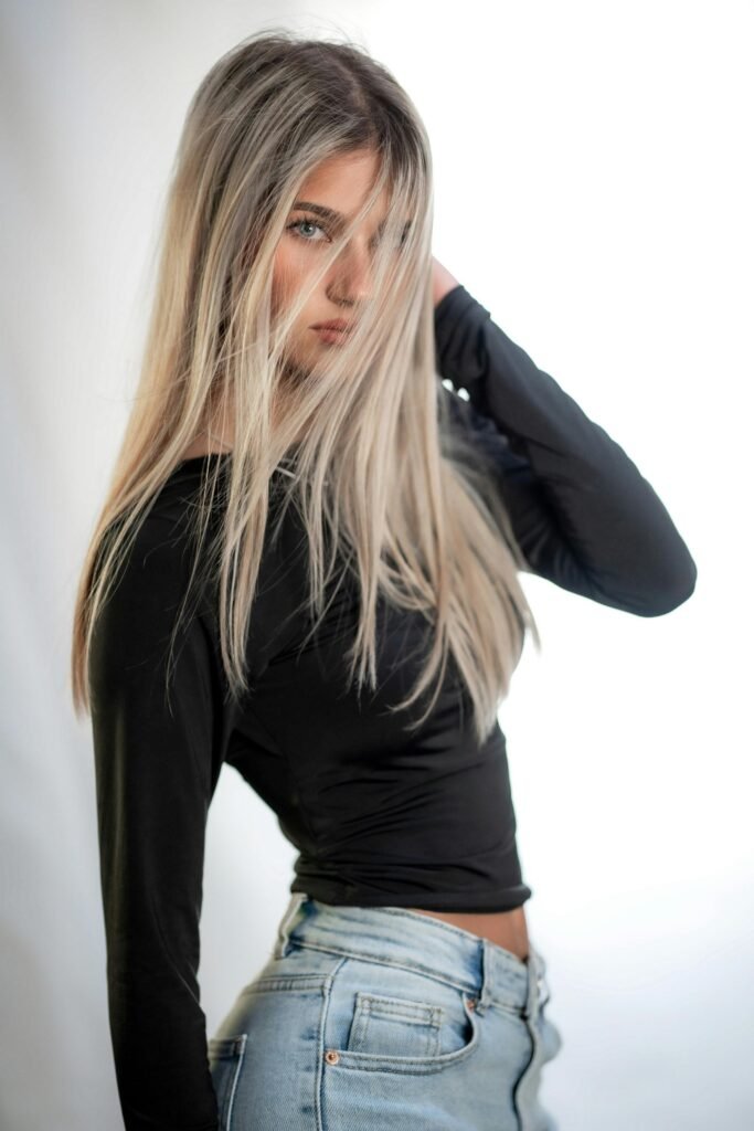 foto de mulher loira cabelos compridos com mechas na frente do rosto uma das mãos nos cabelos