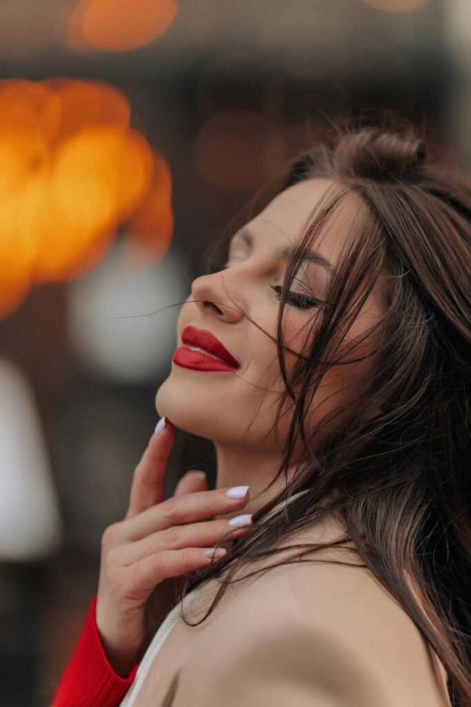 mulher maquiada leve sorriso cabelos presos lisos soltos uma das mãos no queixo lipstick day dia do batom 29 de julho é o dia do batom