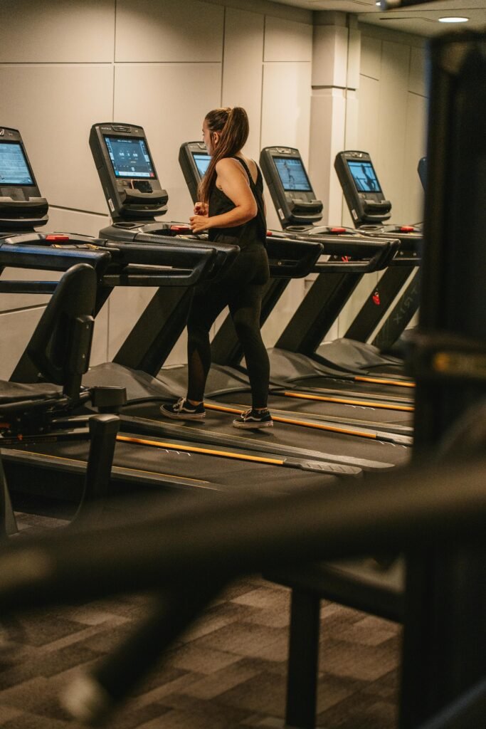 mulher caminhando em esteira de academia fazendo atividade física perder gordura na barriga