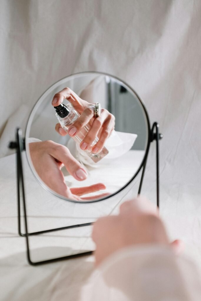 foto de uma mulher passando perfume no punho aparecendo um espelho redondo