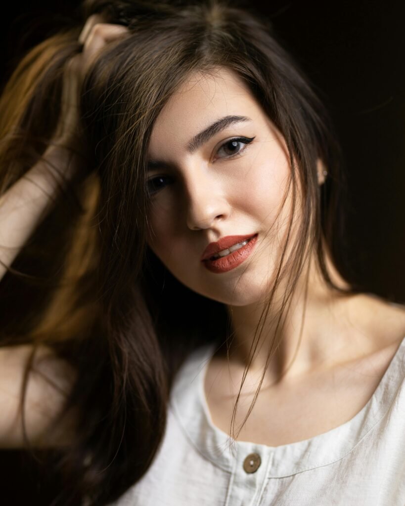 mulher jovem branca cabelos lisos olhos castanhos claros leve maquiagem cabeça levemente torta e uma das mãos na cabeça, preocupada