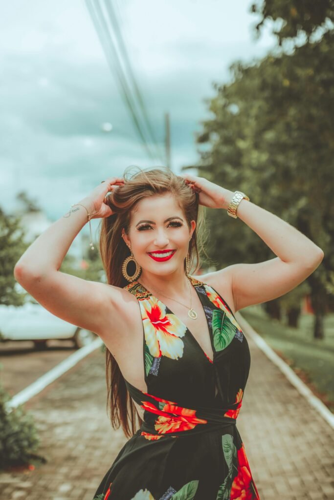 loira sorrindo batom vermelho cabelos longos lisos soltos vestido preto florido brincos grandes redondo relógio no braco