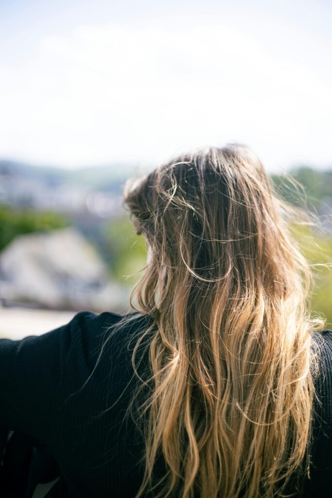 mulher de costas com cabelos compridos loiros, blusa na cor preta