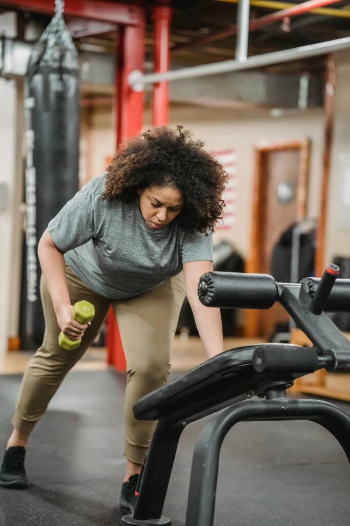 foto de uma mulher morena cabelos crespos fazendo exercício para perder peso em academia (Açúcar e energia o doce que engana?)