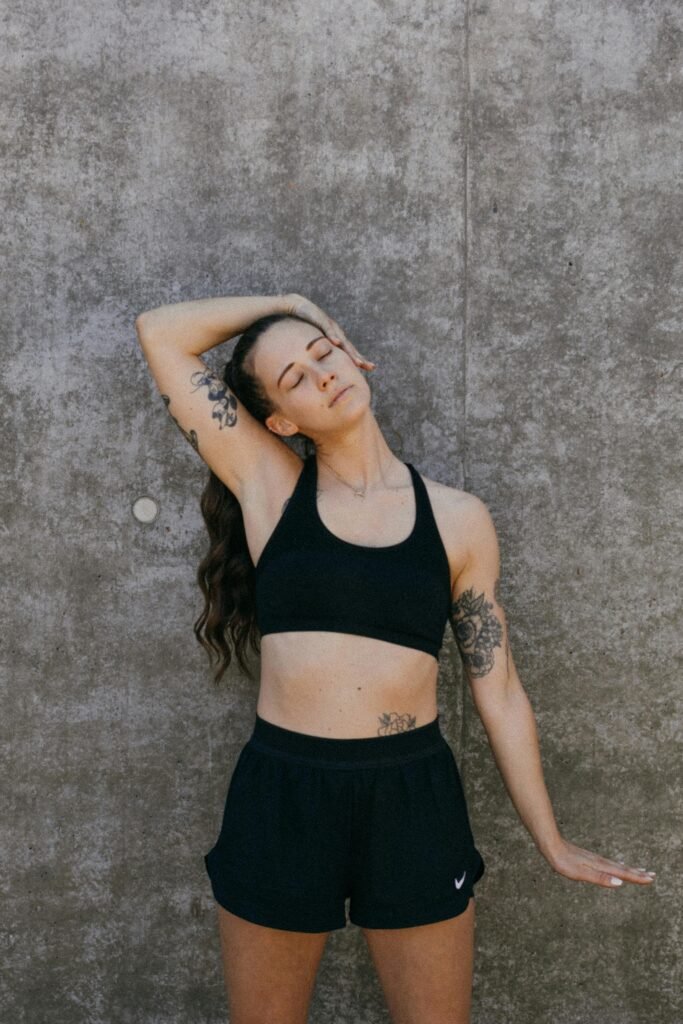 foto de mulher com tatuagens com sutiã e shorts preto fazendo alongamento para corrida