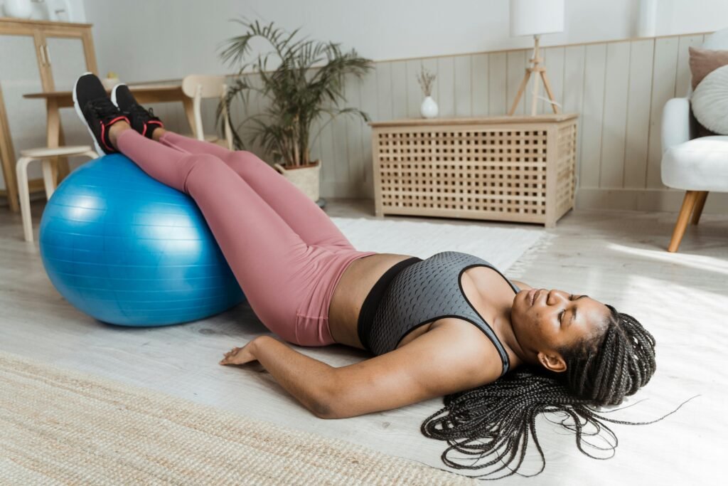 mulher praticando pilates em casa com uma bola grande azul