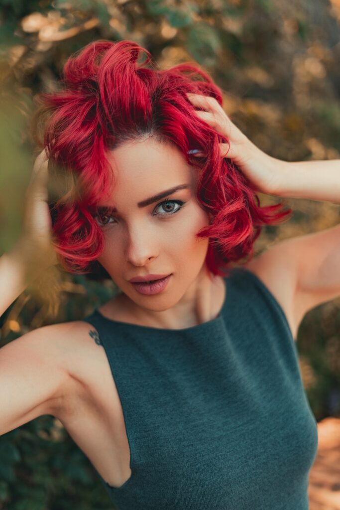 mulher jovem branca cabelos médios vermelhos esta segurando os cabelos fazendo uma pose pra self