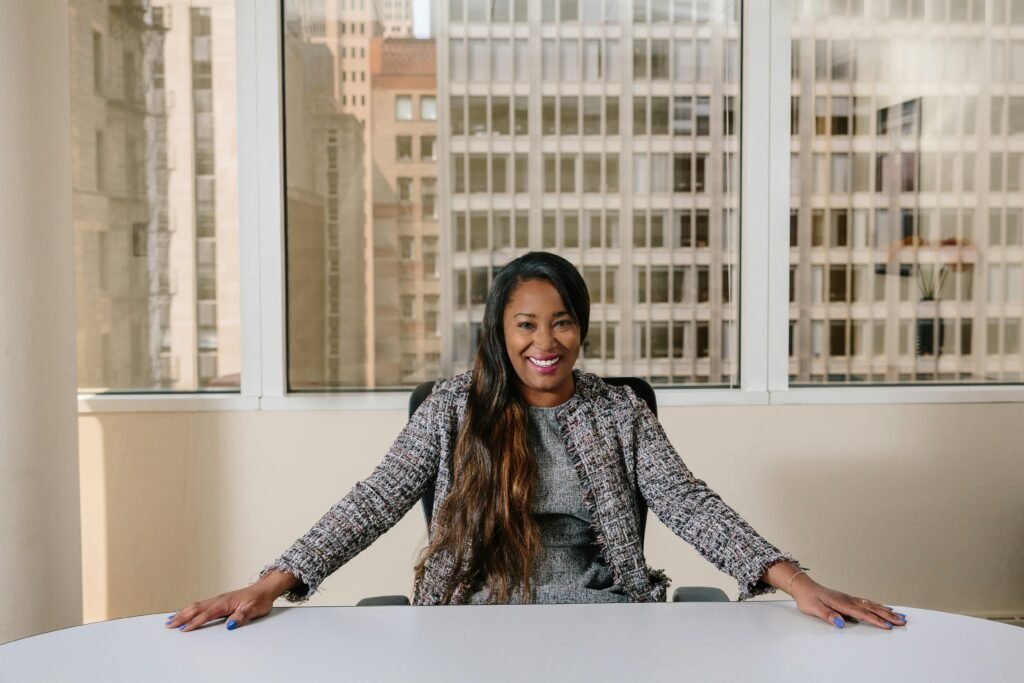 empresaria mulher preta linda sorrindo bracos abertos sobre a mesa. cabelos longos lindos lisos well cared for hair cabelos bem cuidados cabeleireira bem informada