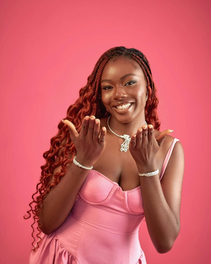 mulher jovem preta linda sorrindo cabelos compridos vermelhos com transas no inicio, vestido na cor rosa 10 dicas para pintar o cabelo de vermelho