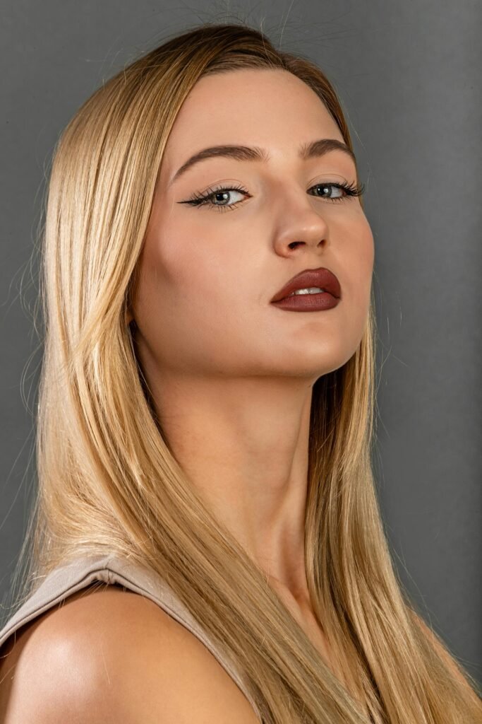 mulher loira maquiada batom vermelho olhos azuis claros cabelos lisos longos loiros