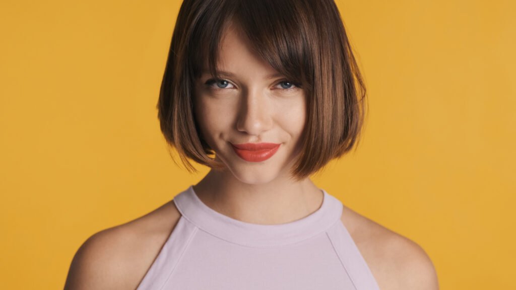 mulher leve maquiagem e sorriso olhos azuis cabelo estiloso corte bob cut corte chanel blusinha branca estilosa