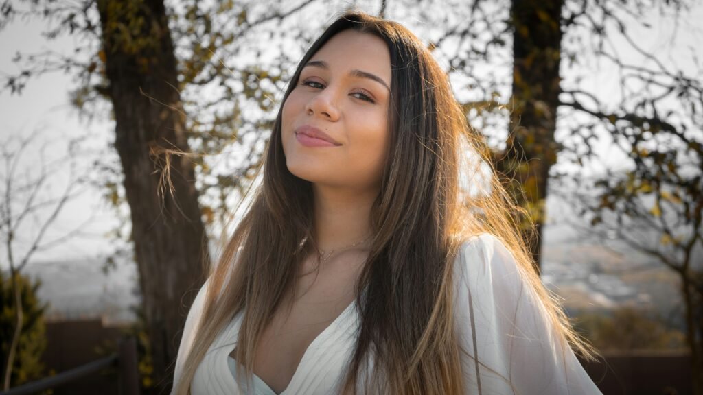 mulher sorrindo cabelos compridos lisos castanhos blusinha branca estilosa