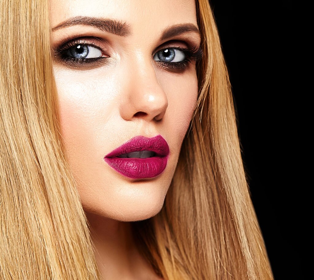 mulher loira cabelos lisos maquiada batom roxo olhos azuis