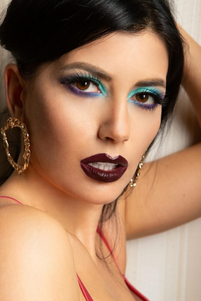 mulher branca linda maquiada batom roxo brincos grandes dourados estilosos cabelos pretos lisos presos vestido vermelho