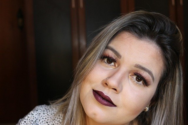 mulher maquiada batom roxo cabelos lisos loiros pequeno brinco olhos castanhos