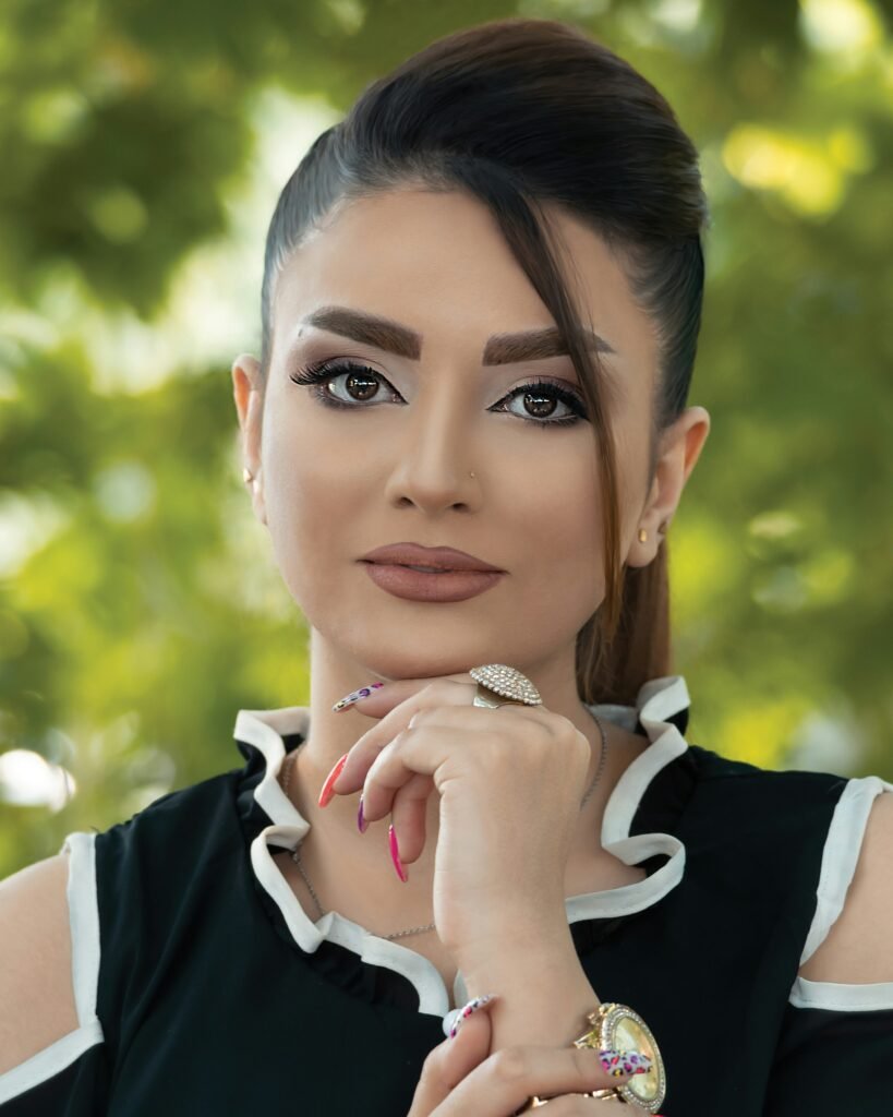 mulher maquiada leve sorriso penteado cabelos presos com uma mexa solta na frente blusinha estilosa branco e preto