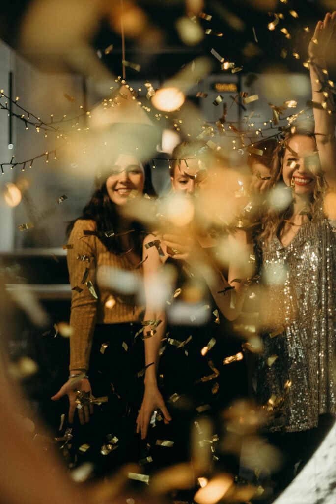 três mulheres sorrindo dançando em uma festa luzes pequenas e brilhos glitters 
