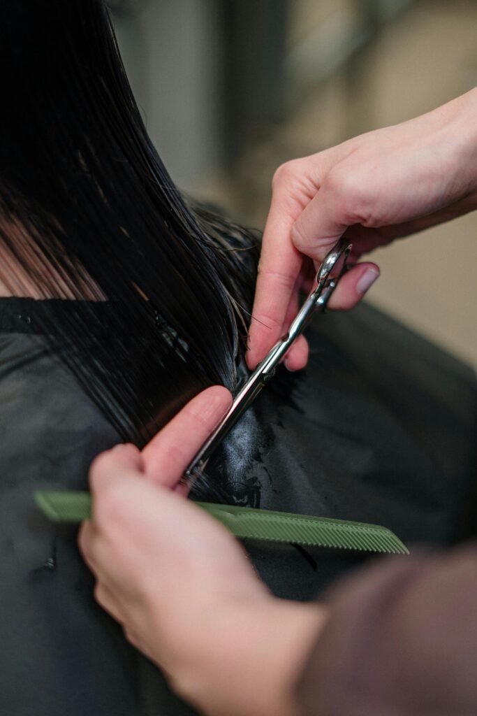 foto ilustrativa de corte de cabelo feminino cabelos pretos lisos molhados tesoura e pente nas mãos