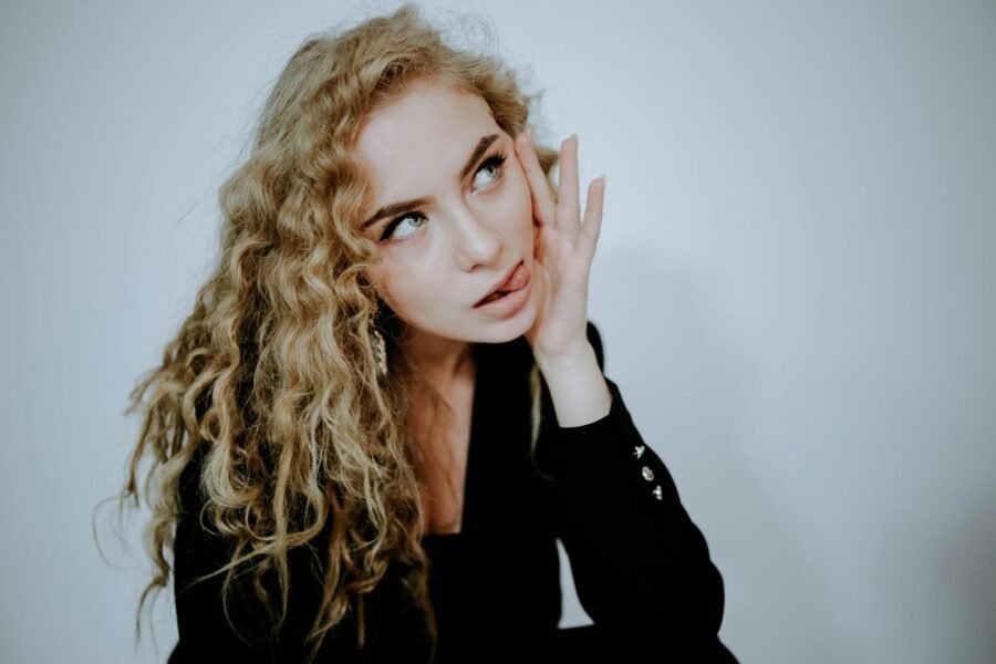 foto de mulher loira mordendo a linguá uma das mãos no rosto