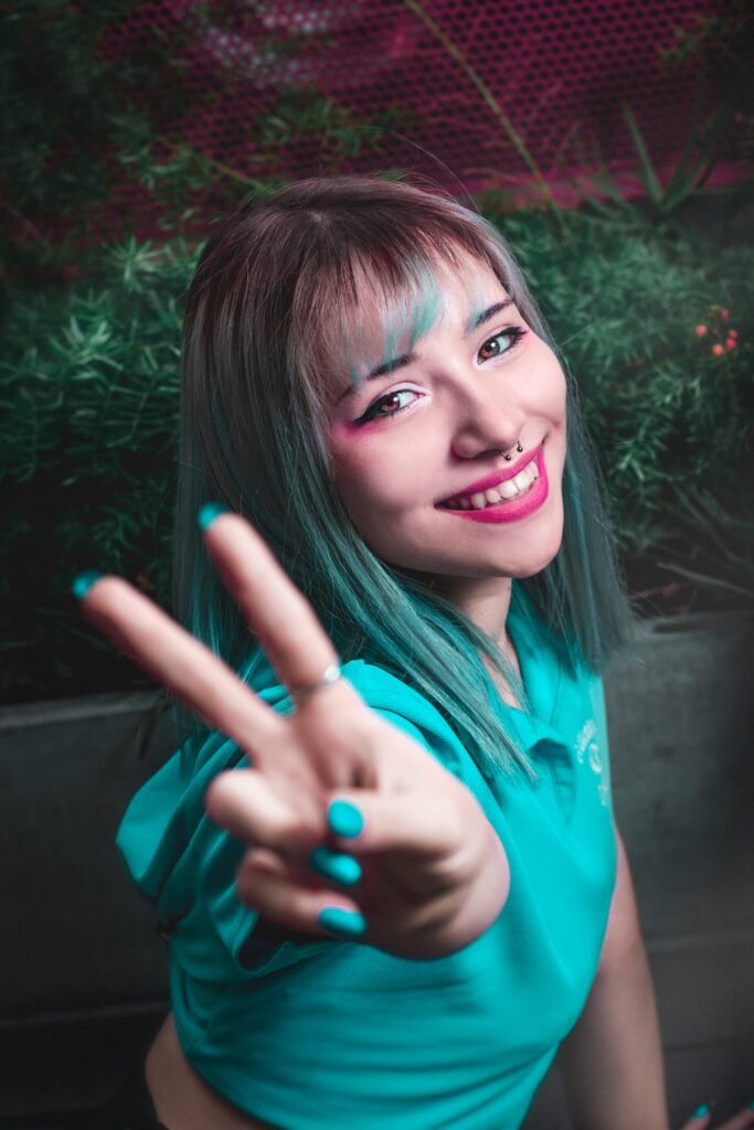 foto de mulher jovem sorrindo maquiada cabelos médios lisos pintados de azul bluee percingi no nariz
