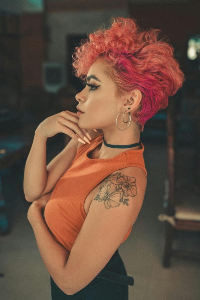 foto de lado de mulher morena cabelos médios pintados de vermelho red brincos argolas grandes maquiada uma das mãos no queixo